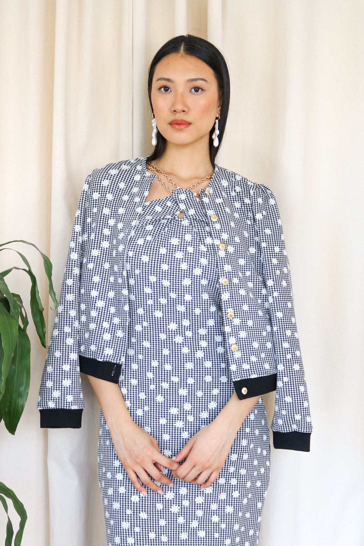 Model wearing the black and white of the jacquard knit cardigan paired with the criss cross gold chain tea dress in black and white. Front facing.