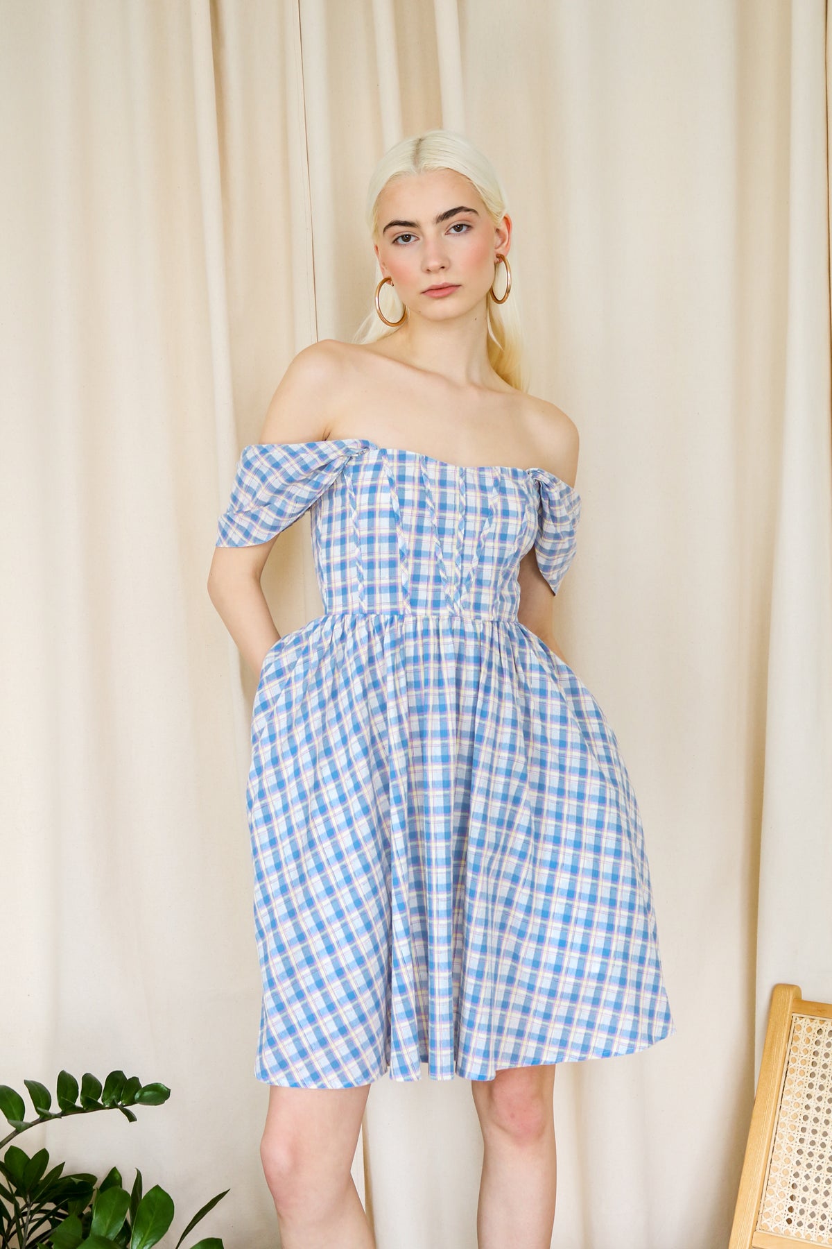 Model wearing the blue plaid off shoulder dress against a neutral background.