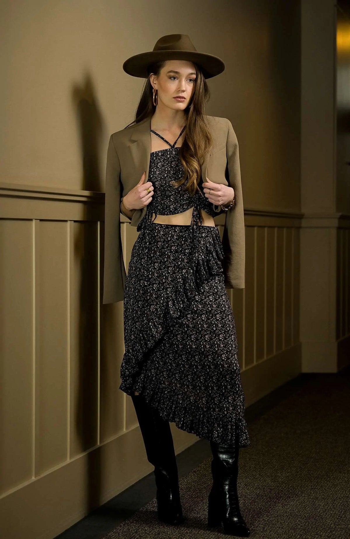 Model wearing an elegant floral asymmetrical midi skirt with ruffled hem, paired with a matching strapless top and gloves, standing in a vintage-inspired room
