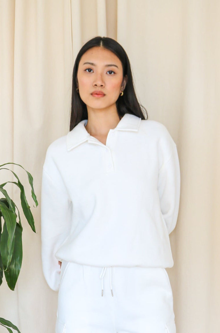 Model wears the white everyday polo oversized cotton sweatshirt with a polo collar against a neutral backdrop. Front facing.