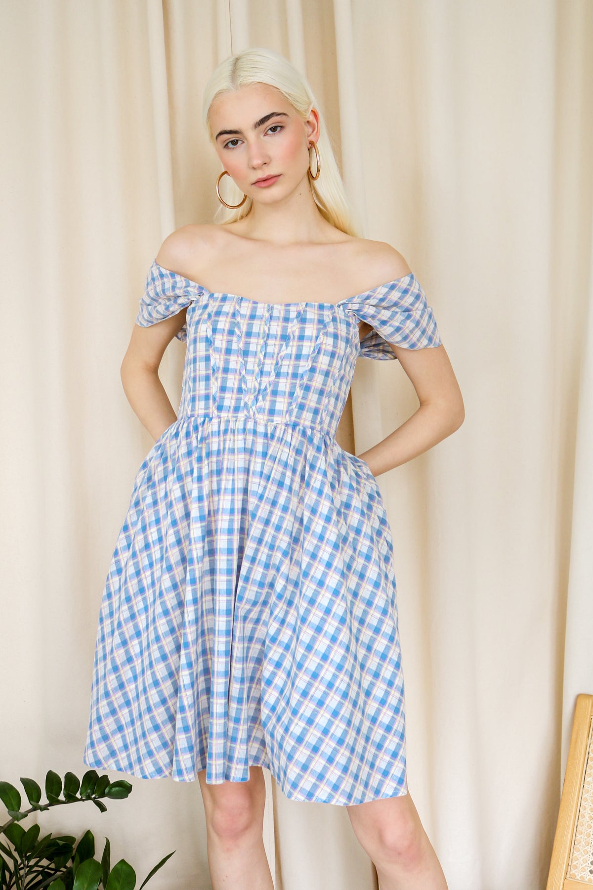 Model wearing the blue plaid off shoulder dress against a neutral background.