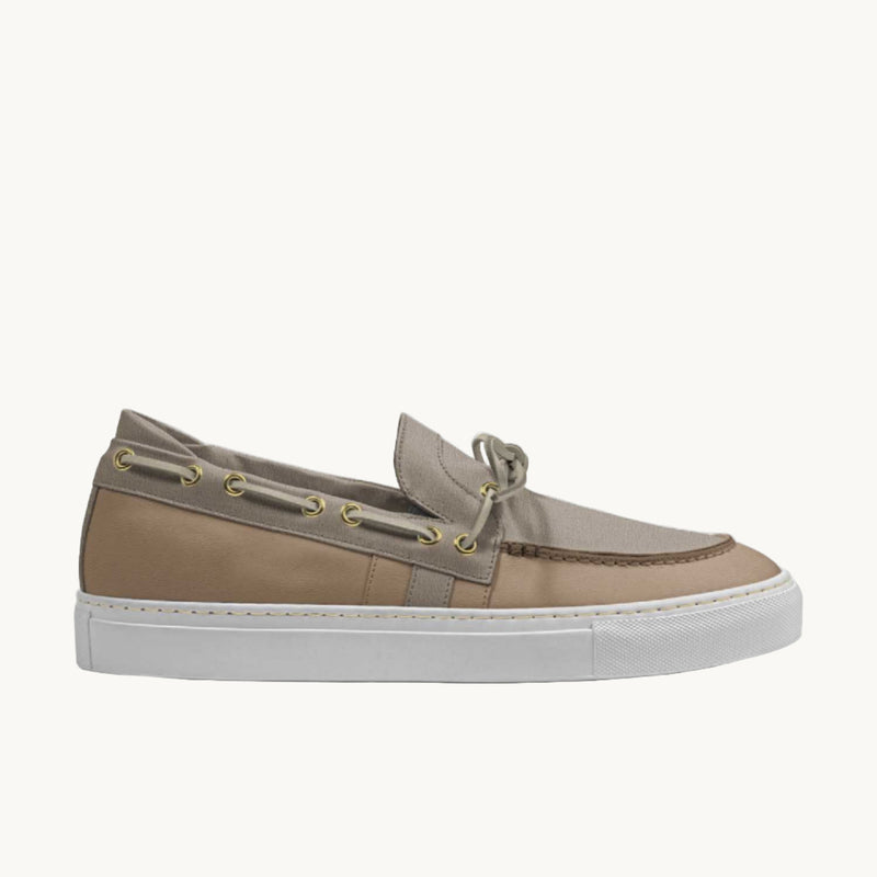 Side view of beige boat loafer sneakers with laces on the side. 