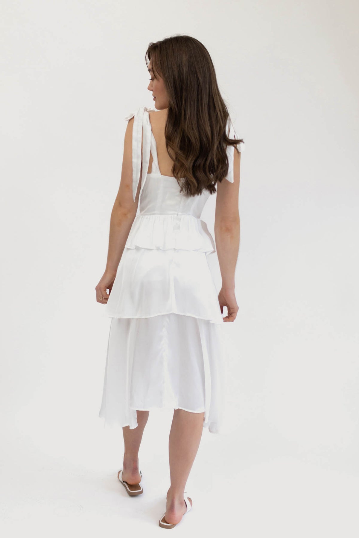 Model wears the Florence Tiered Ruffle Midi dress in white. Back facing.