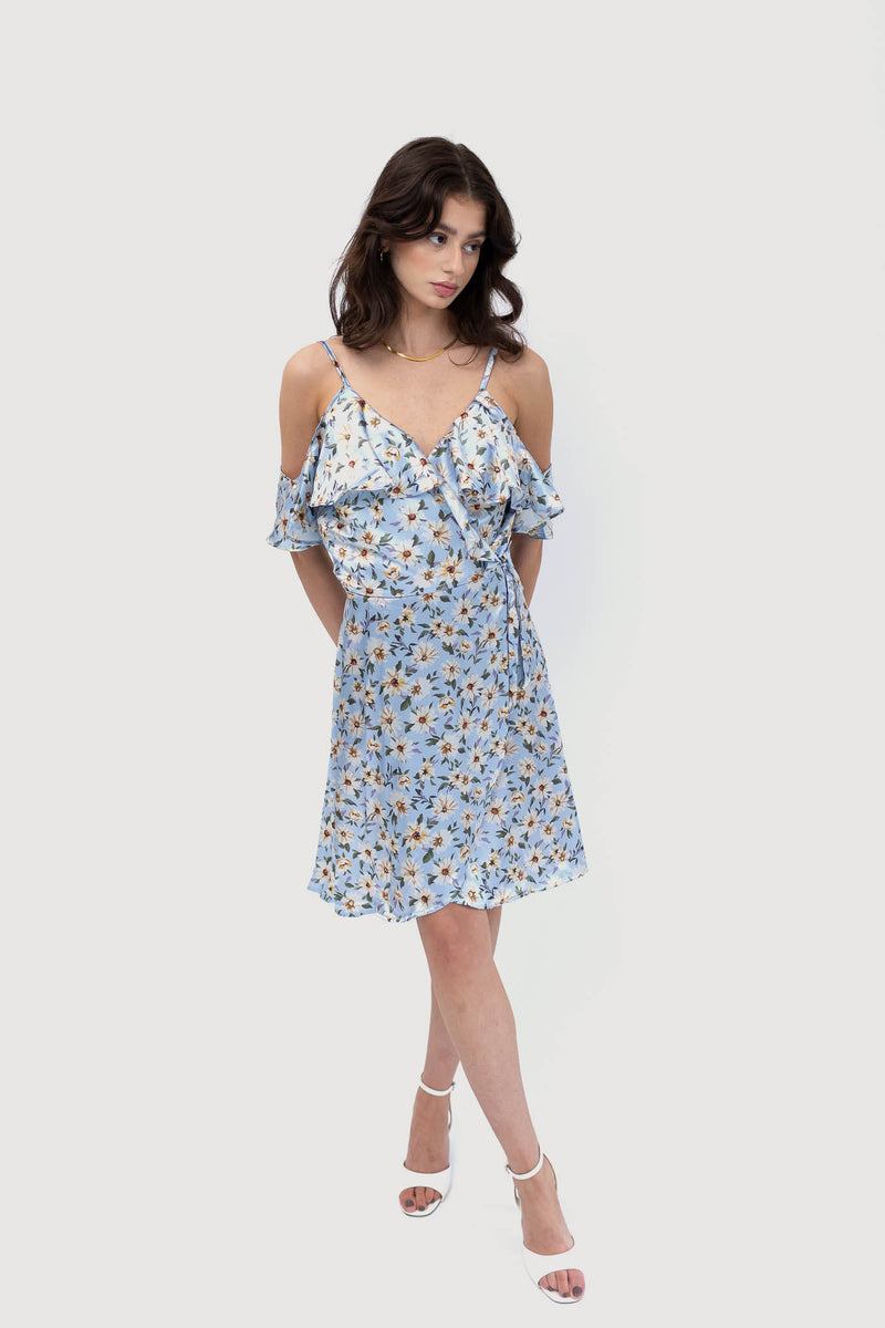 Model wears light blue off the shoulder mini dress with a floral pattern. Facing the front