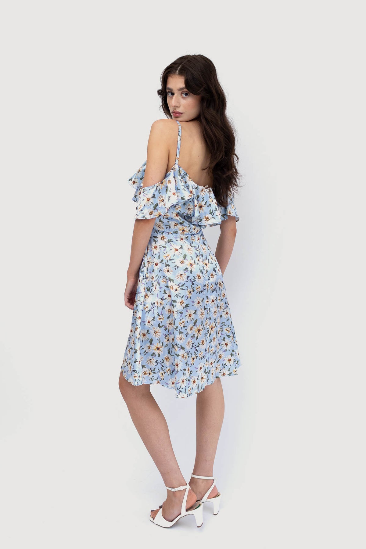 Model wears light blue off the shoulder mini dress with a floral pattern. Showing the back of dress.