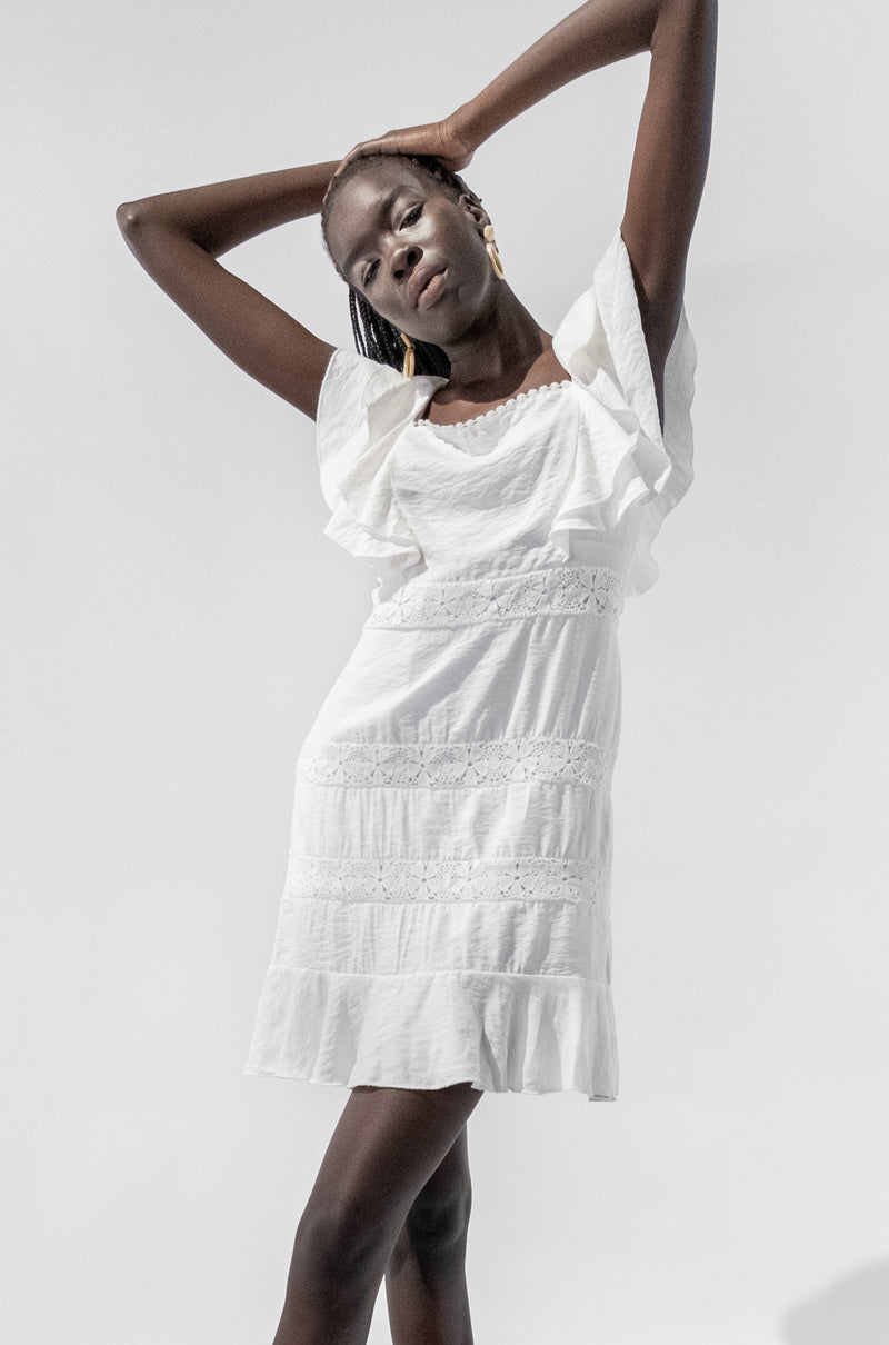 Model wearing white ruffle short sleeves lace dress with square neckline and floral detailing