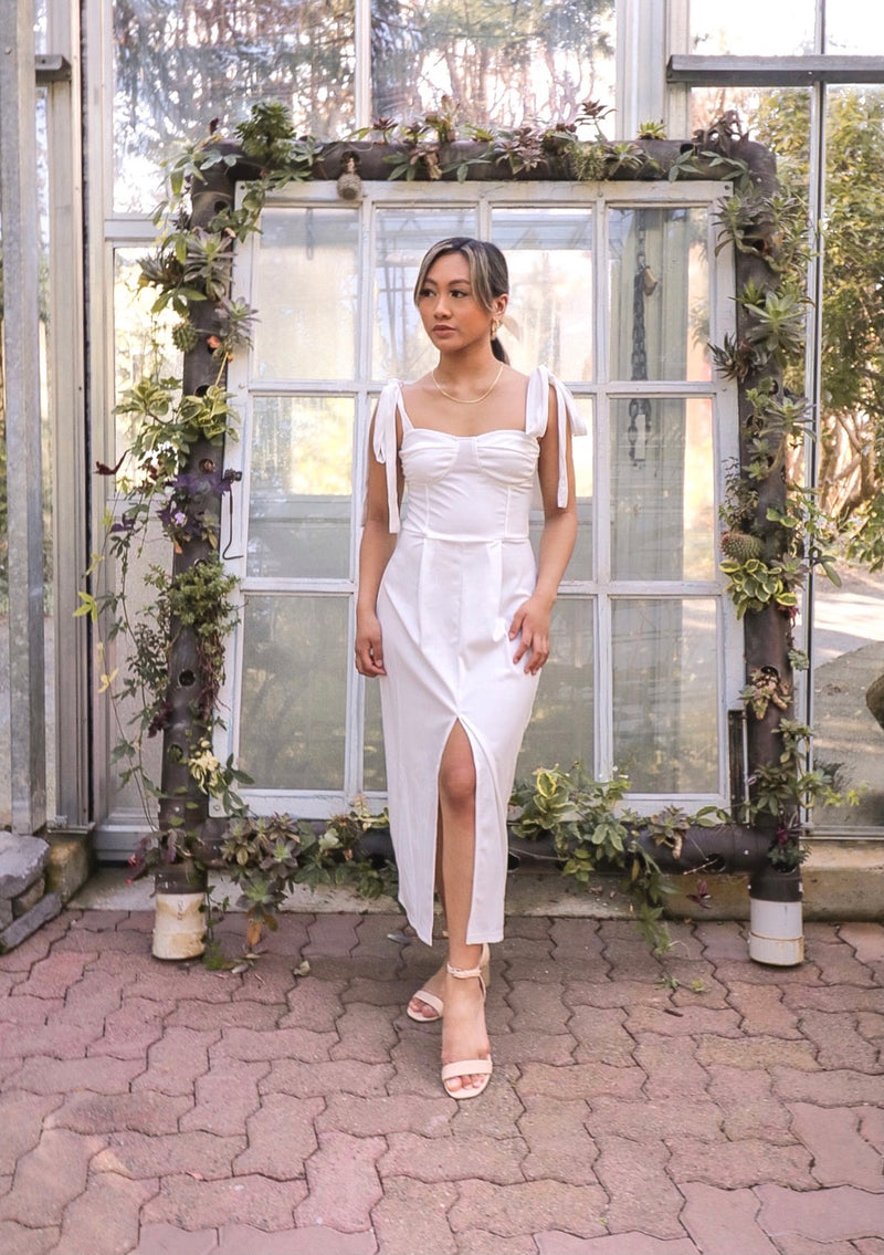 Model standing wearing a tie strap midi dress in white.